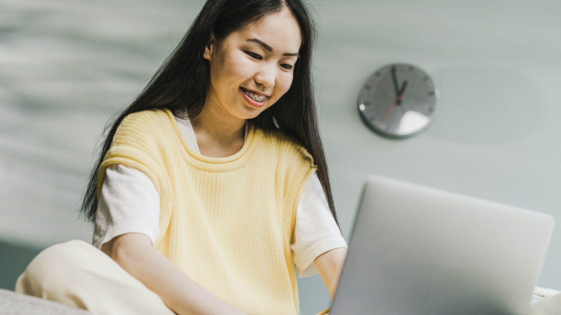 Mulher jovem a sorrir enquanto digita num portátil num ambiente de trabalho descontraído